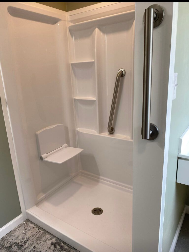 White accessible shower with a fold-down seat and grab bars.