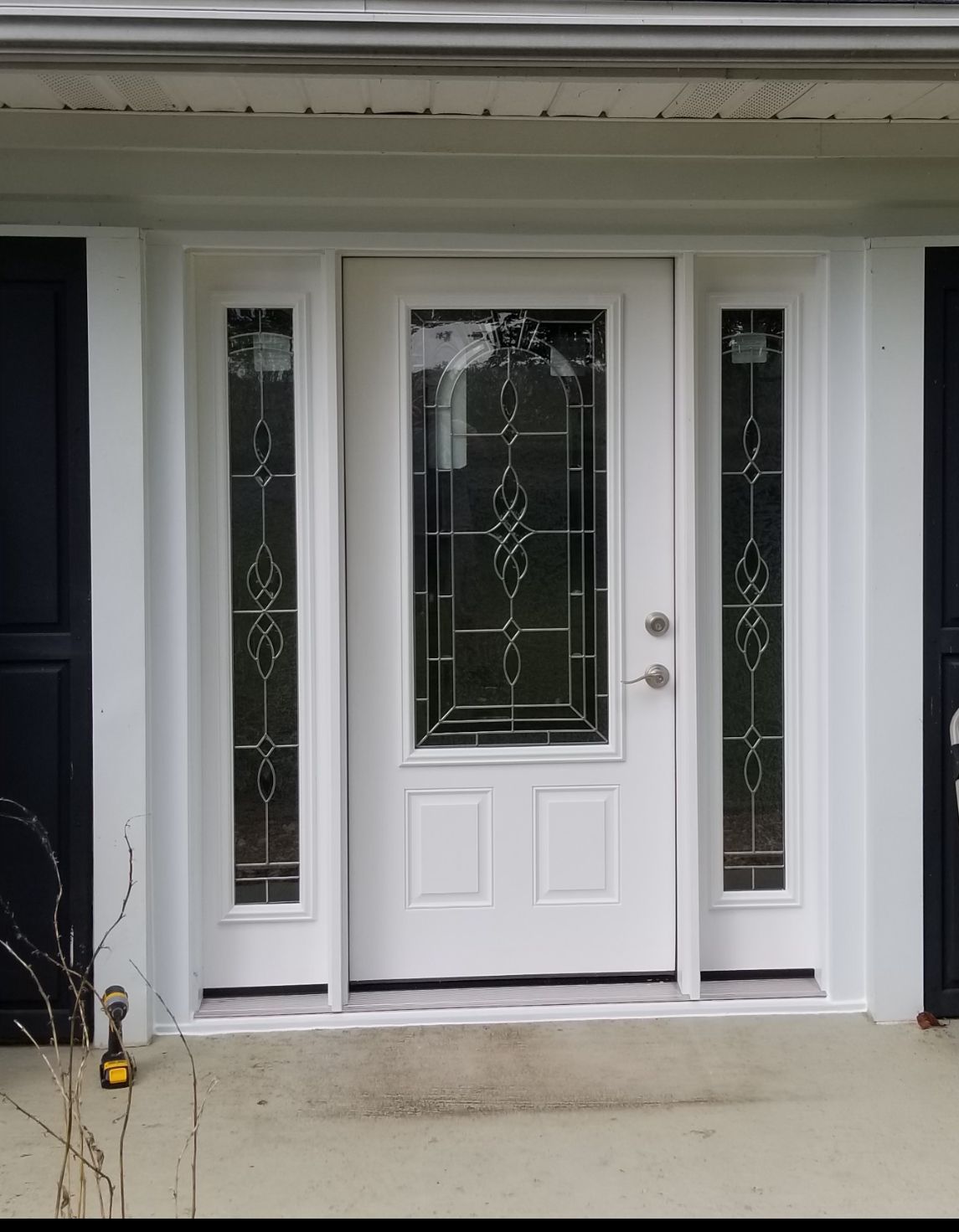 White front door with sidelights, under a white awning. Black shutters flank the door.