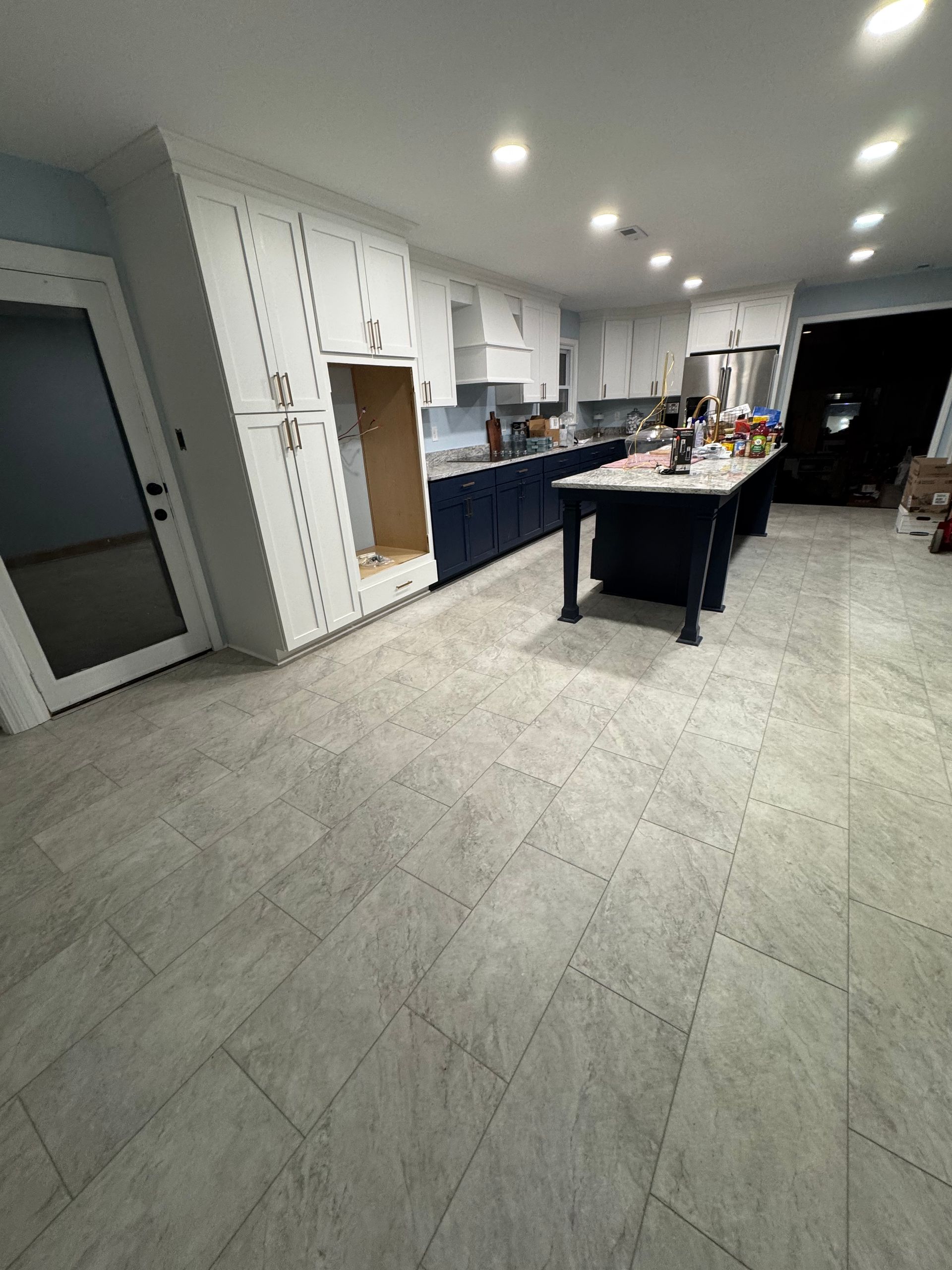Kitchen with white cabinets, blue island, and gray tile flooring.