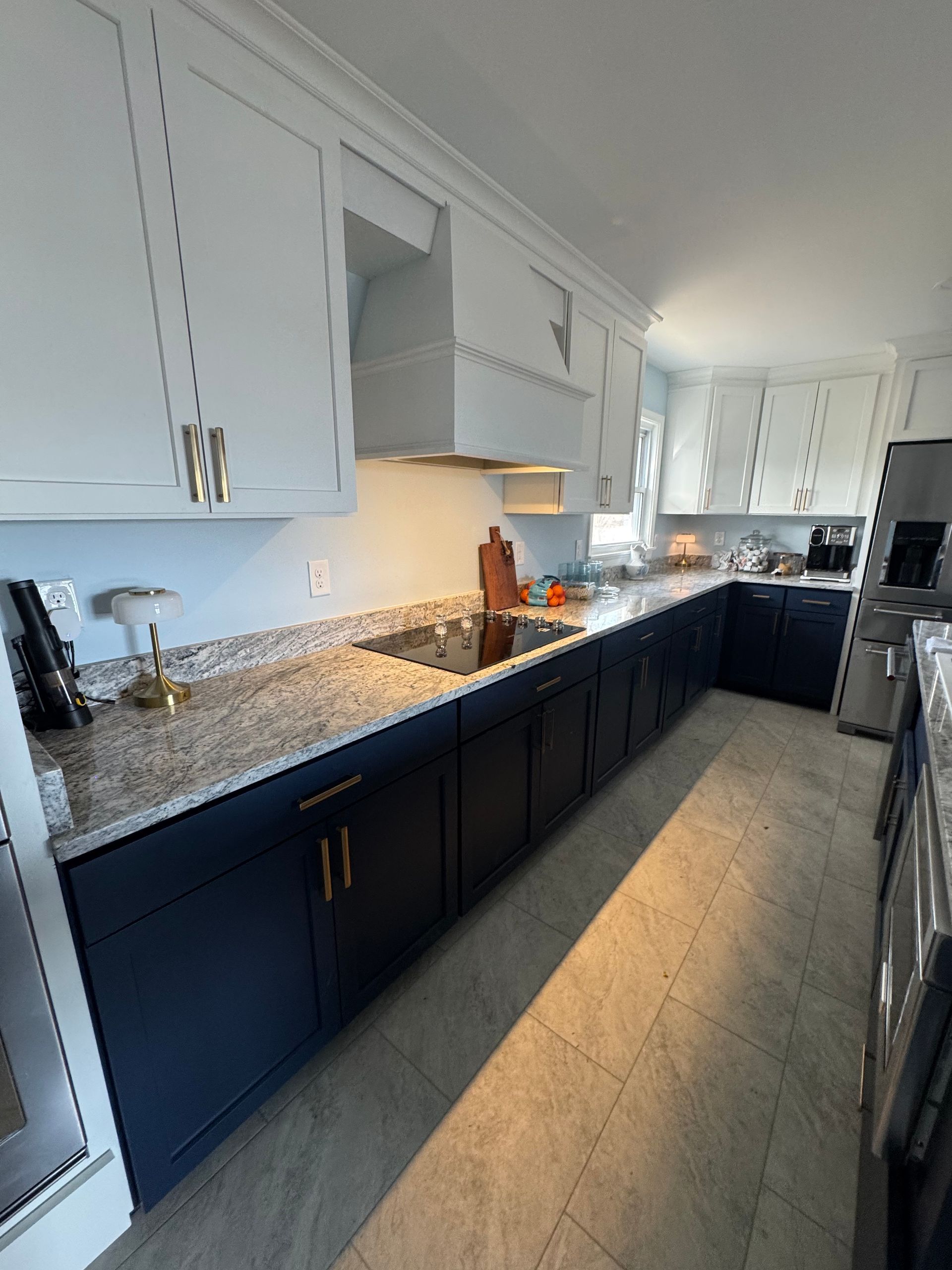 Kitchen with navy blue cabinets, white upper cabinets, and granite countertops.