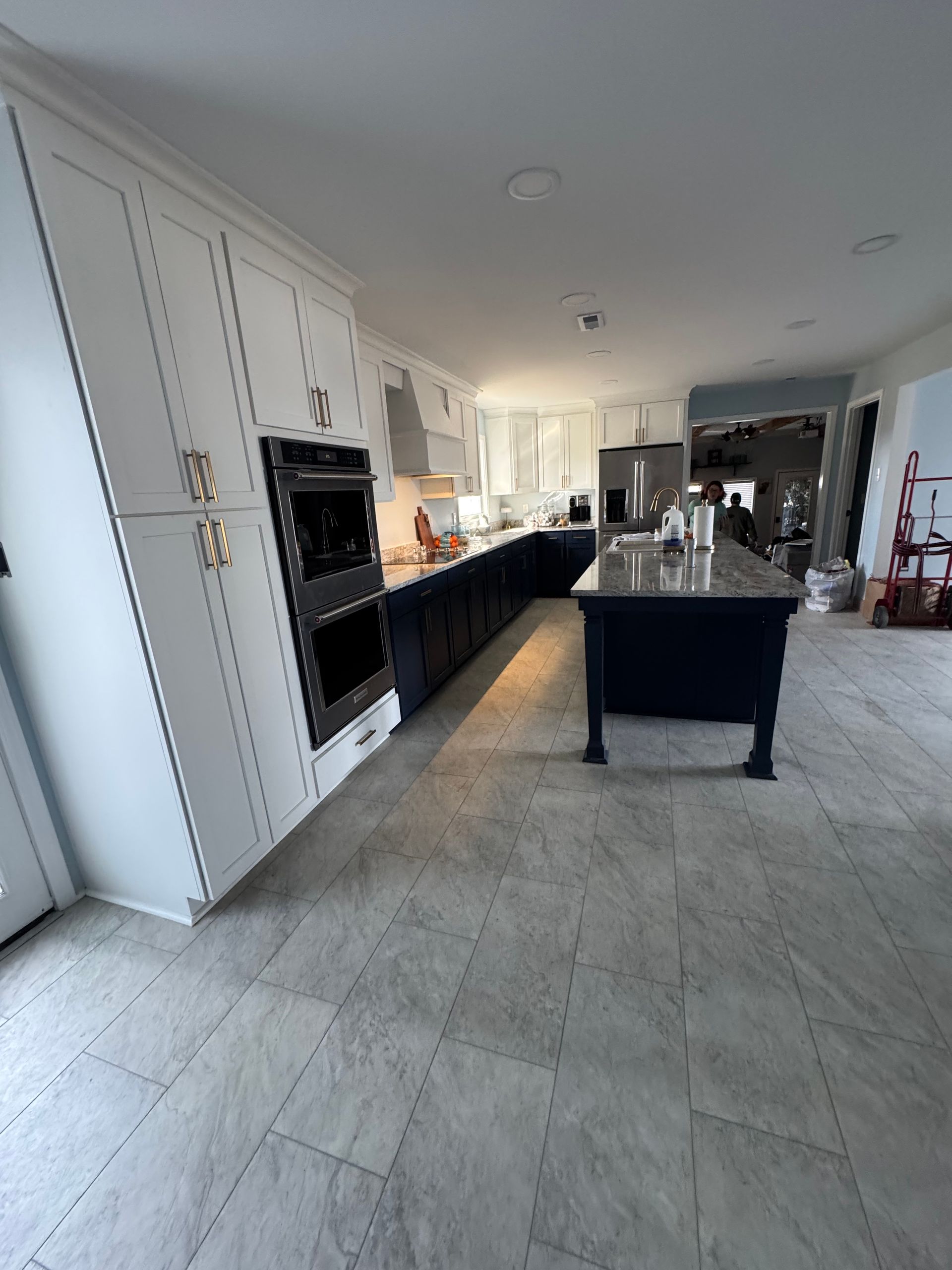 A kitchen with white cabinets, blue island and cabinets, and a tile floor.