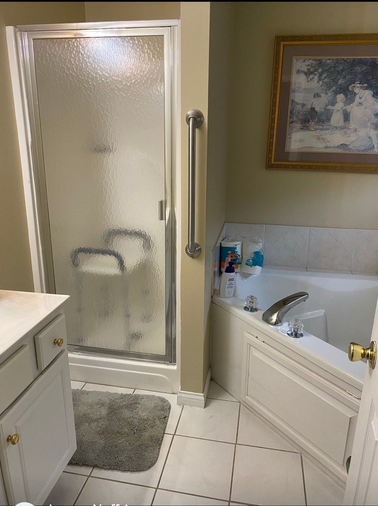 Bathroom with shower, tub, and vanity; white tile floor, cream walls, and a painting.