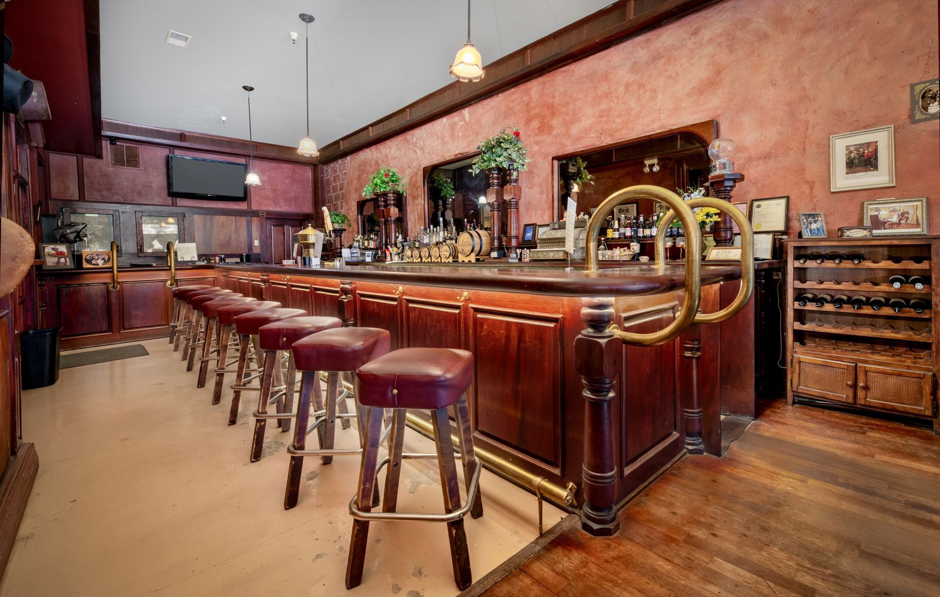 A long wooden bar with stools in a restaurant.