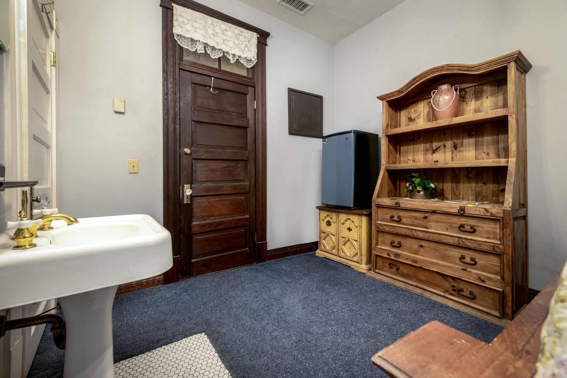 A bathroom with a sink , dresser , and door.