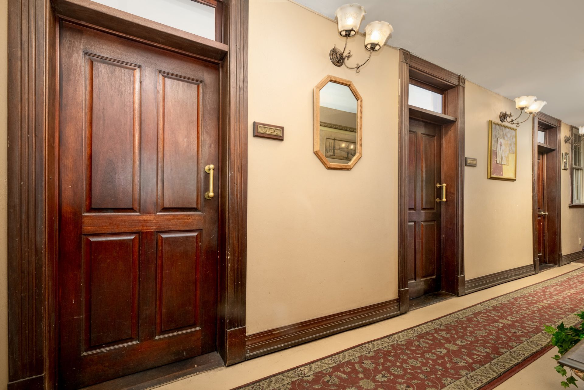 A hallway with wooden doors and a mirror on the wall