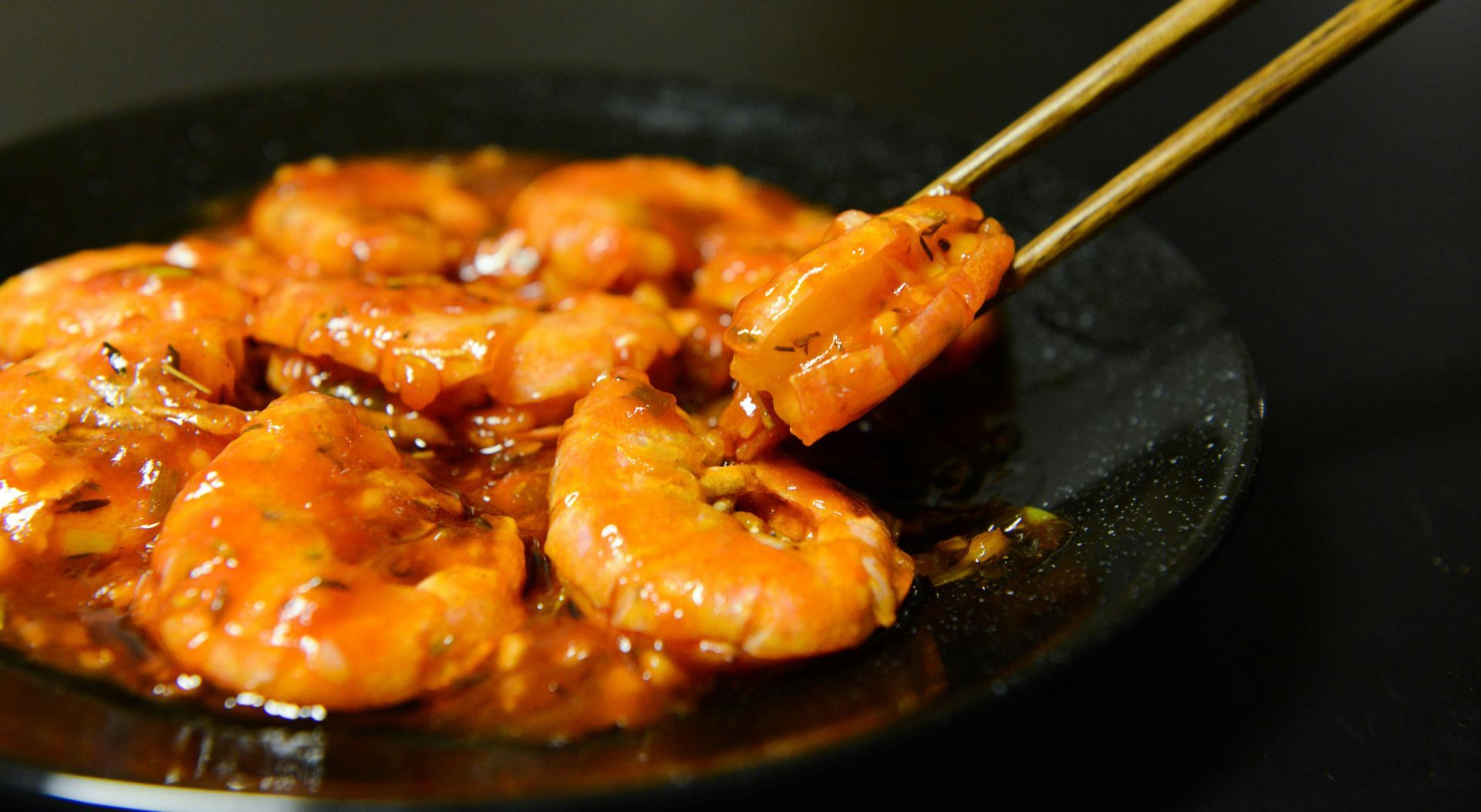 A close up of a plate of shrimp with chopsticks.