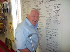 A man with crutches is standing in front of a white board.