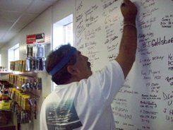 A man is writing on a white board in a store.