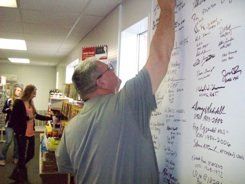 A man is writing on a white board in a room.