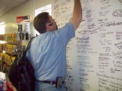 A man is writing on a white board in a store.