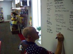 A man is writing on a white board in a store.