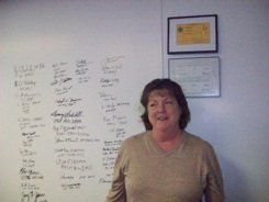 A woman is standing in front of a white board with writing on it.
