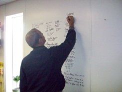 A man is writing on a whiteboard with a marker.