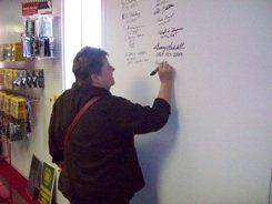 A man is writing on a whiteboard in a store.