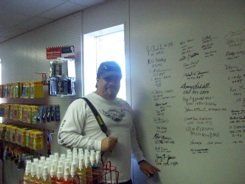 A man is standing in front of a white board with writing on it.