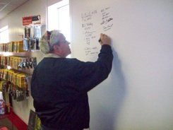 A man is writing on a white board in a store