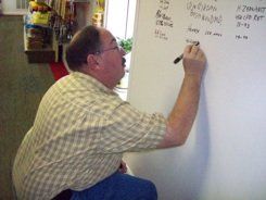 A man is writing on a white board with a marker.