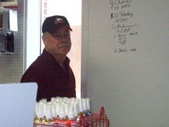 A man is standing in front of a white board with writing on it.