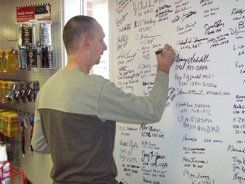 A man is writing on a whiteboard in a store.