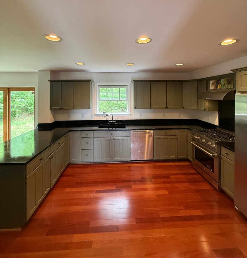 Modern kitchen with dark cabinets, granite island, stainless steel appliances, and pendant lights