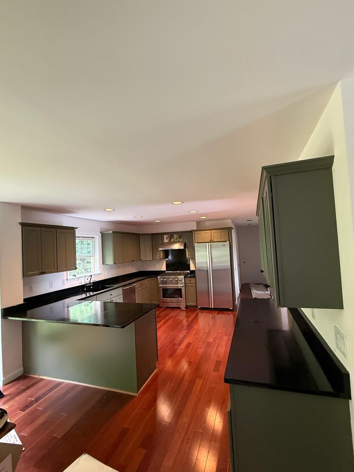 Bright white kitchen with black countertops and a black-and-white checkered floor, stainless appliances.