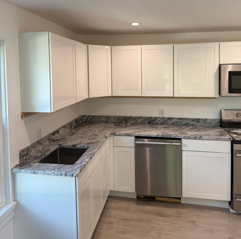 Modern kitchen with black and white cabinets, island seating, stainless fridge, and pendant lights