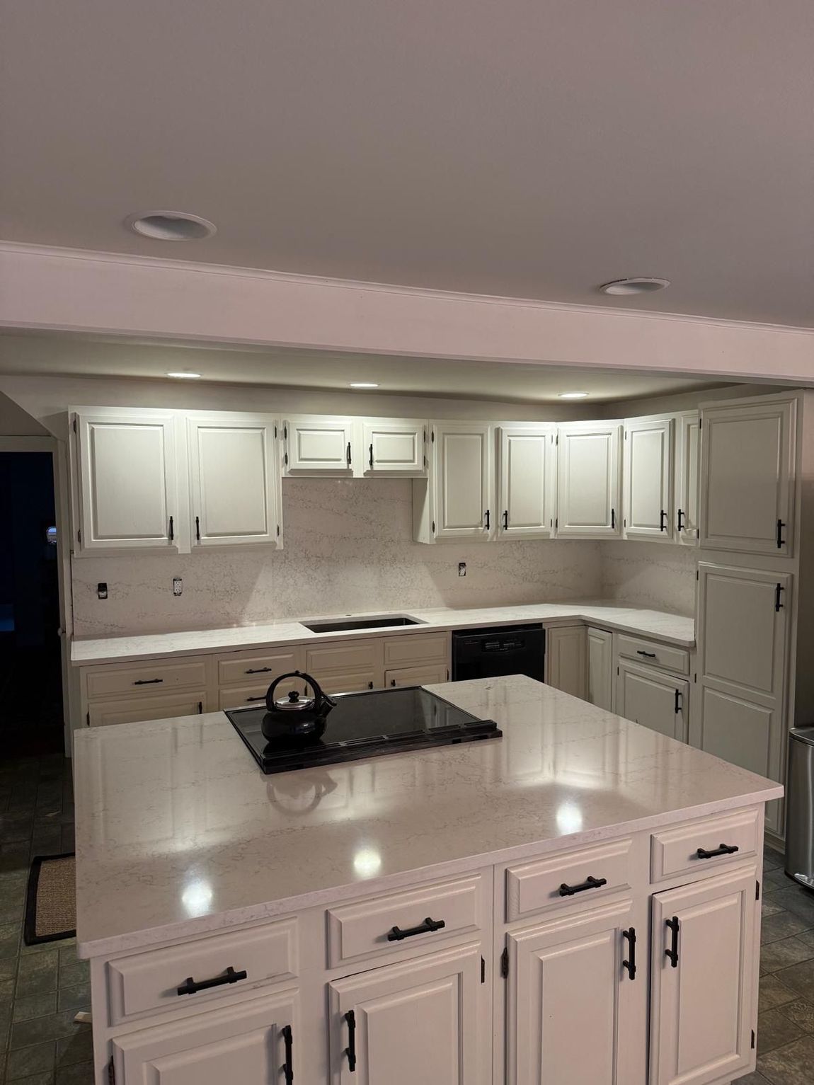Bright modern kitchen with marble island, white cabinets, and large cooking range.