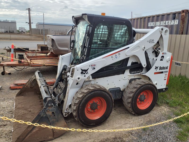 White Bobcat skid-steer loader with a bucket, orange wheels, and black cab parked outdoors.