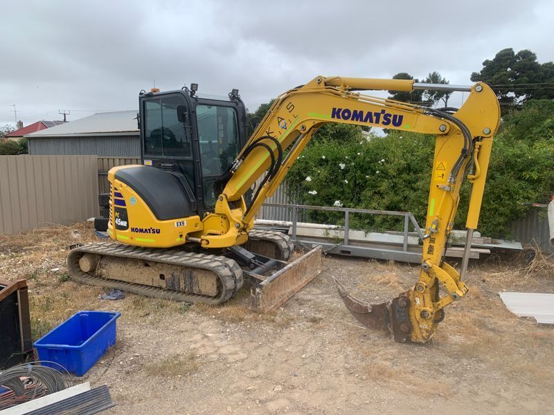 Yellow Komatsu mini excavator on a construction site.