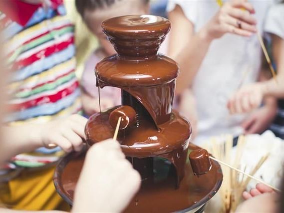 A group of children are enoying a chocolate fountain.