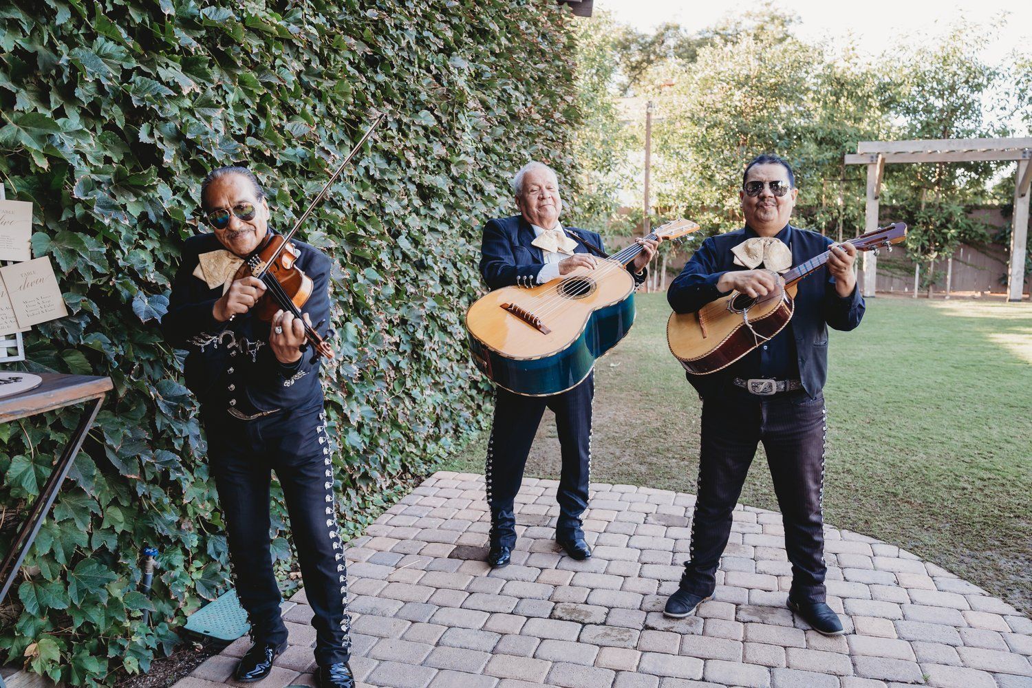 Three men are standing next to each other playing guitars and violins.