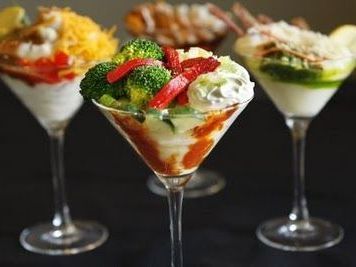 Three martini glasses filled with different types of food