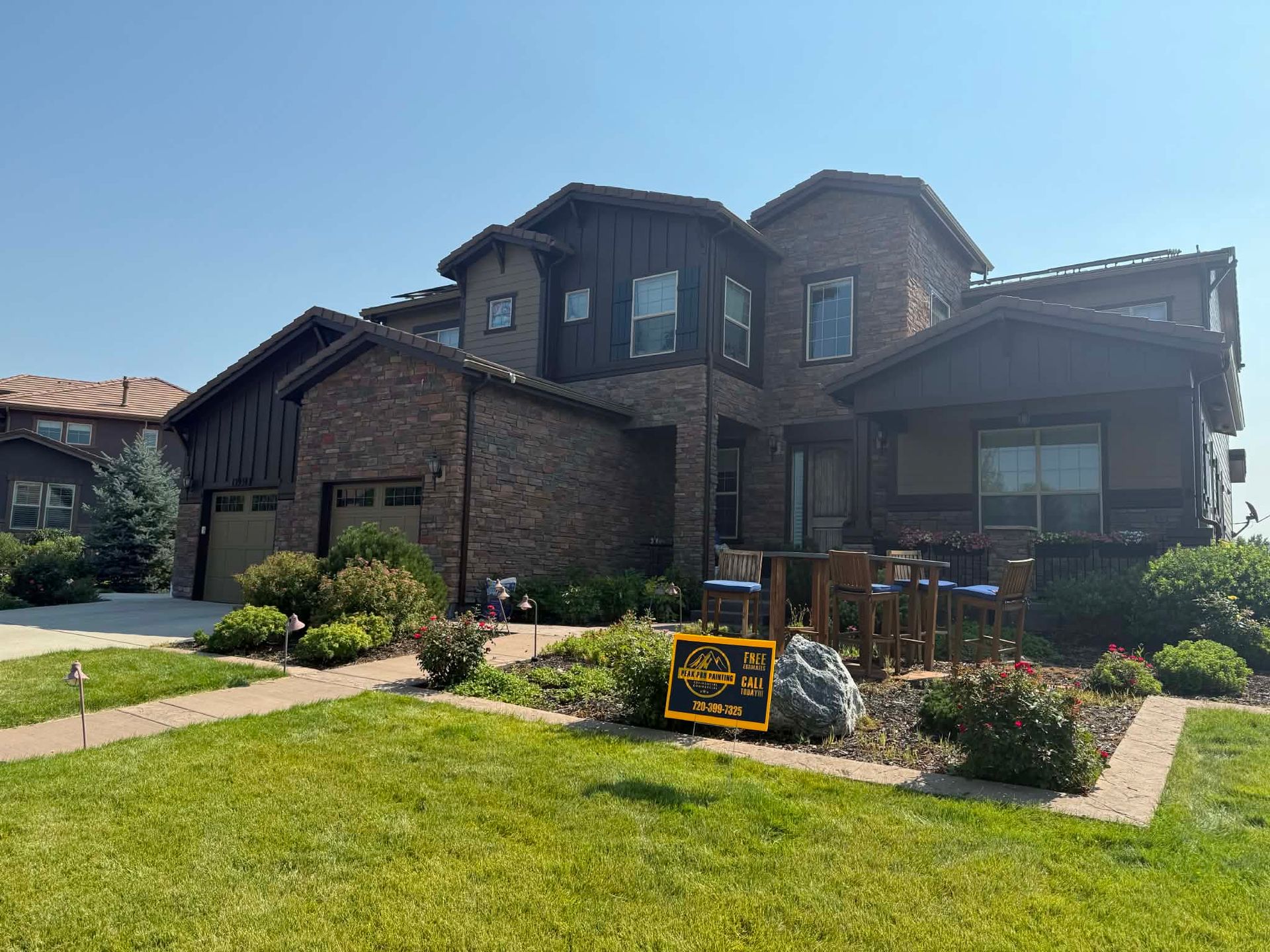 Two-story brick house with a manicured front lawn, landscaping, and a real estate sign in the yard