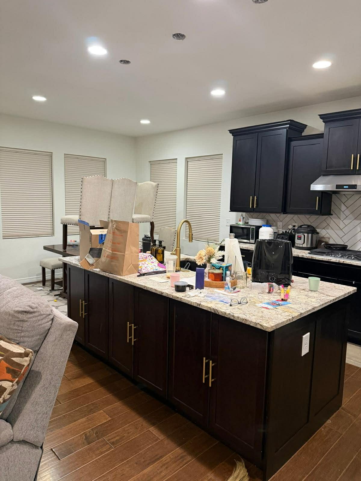 A modern kitchen featuring a dark brown island, granite countertops, and dark cabinets set against white walls.