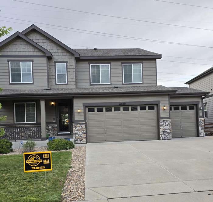 A two-story taupe house with a stone-accented garage and a 