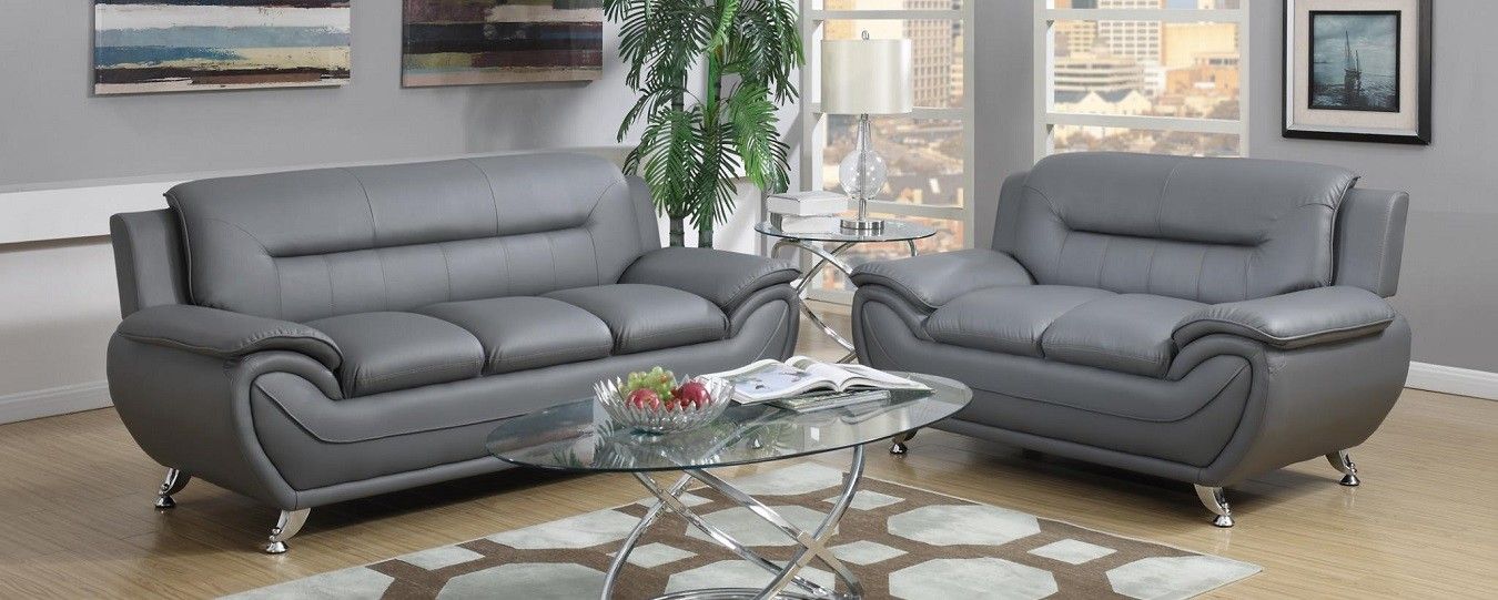 A living room with two grey leather couches and a glass coffee table.