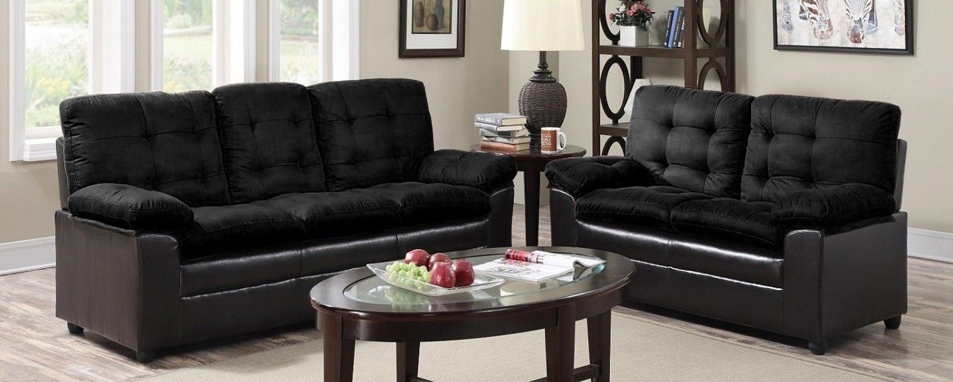 A living room with two black couches and a coffee table