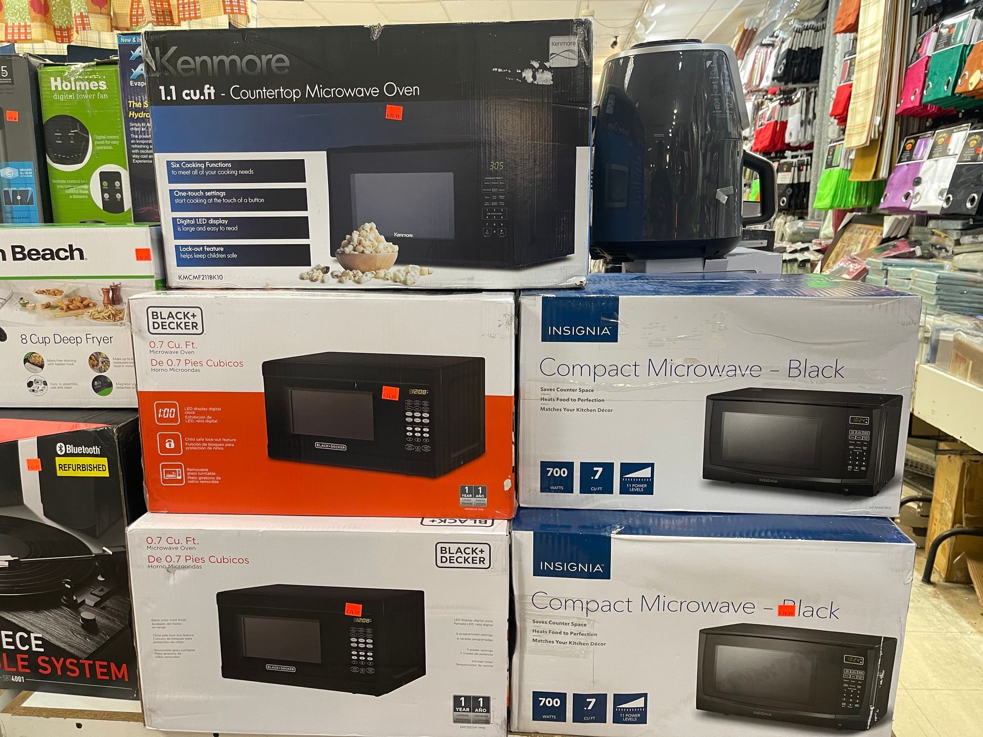 Boxes of microwave ovens are stacked on top of each other in a store.