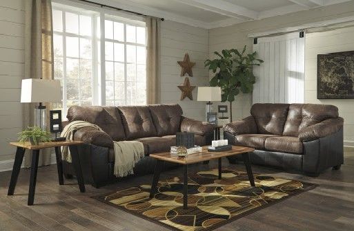 A living room with two brown leather couches , a coffee table , and a rug.