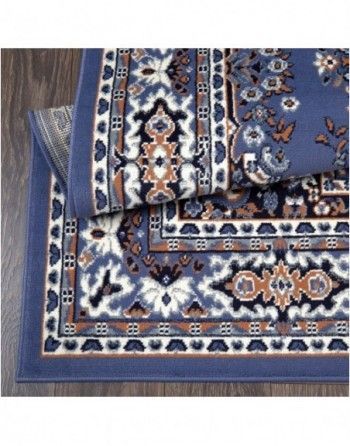 A blue rug with a floral pattern is stacked on top of each other on a wooden floor.