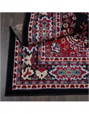 A rug with a black border is laying on a wooden floor.