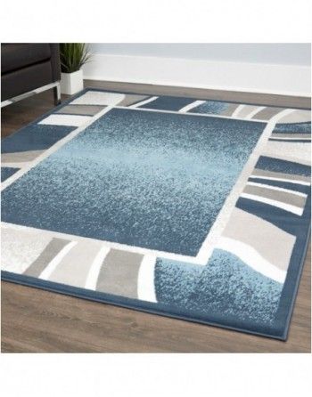 A blue and gray rug is sitting on a wooden floor in a living room.