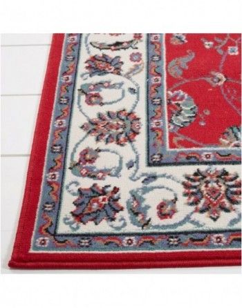 A red rug with a white border and flowers on it