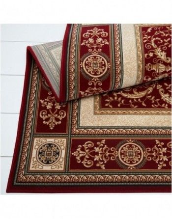 A red rug with a gold border is laying on a white surface.