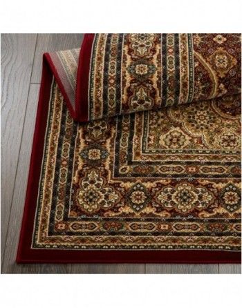 A rug with a red border is on a wooden floor.