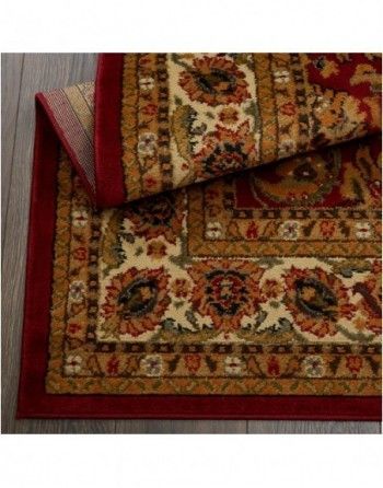 A rug with a red border is laying on a wooden floor.