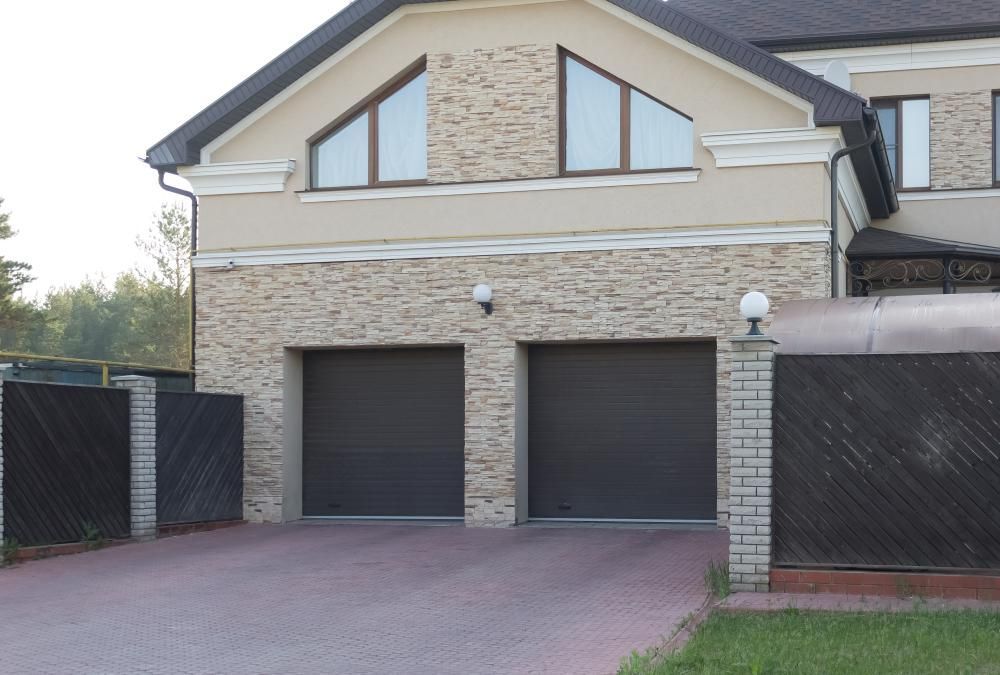 A Large House With Two Garage Doors And A Driveway — Mick’s Garage Doors In Alice River, QLD
