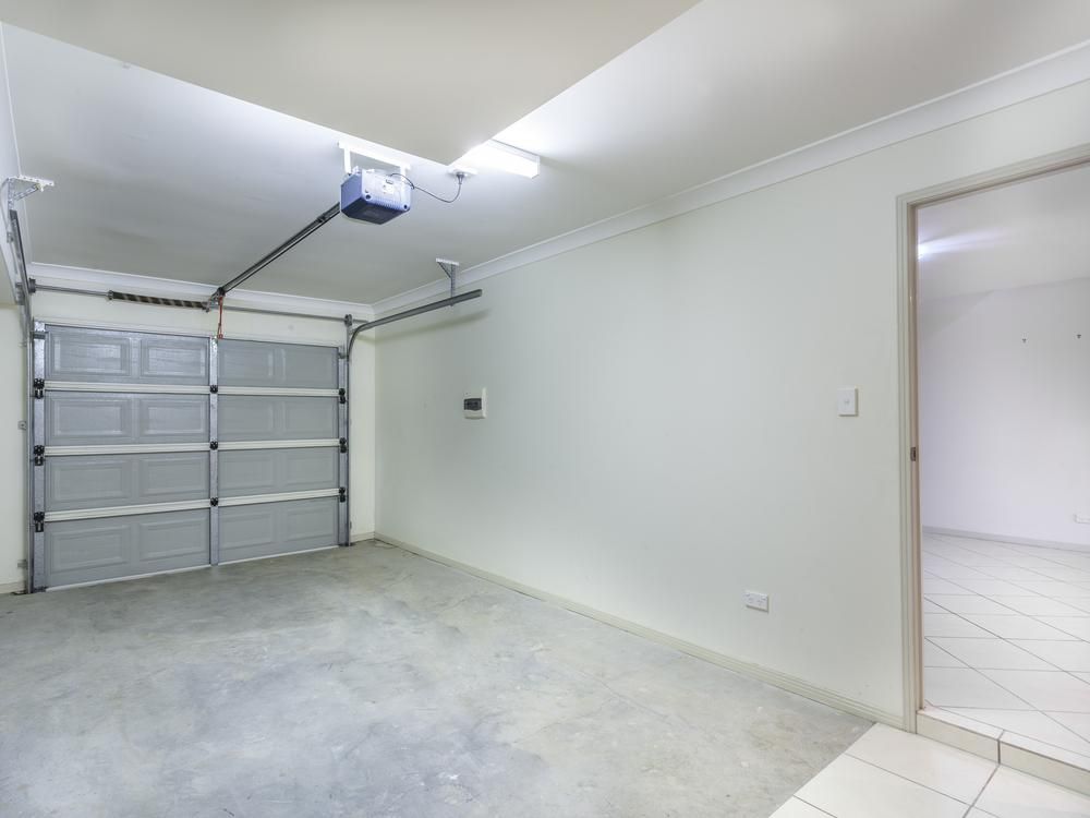 An Empty Garage With A Garage Door Closed And A Light On The Ceiling — Mick’s Garage Doors In Alice River, QLD