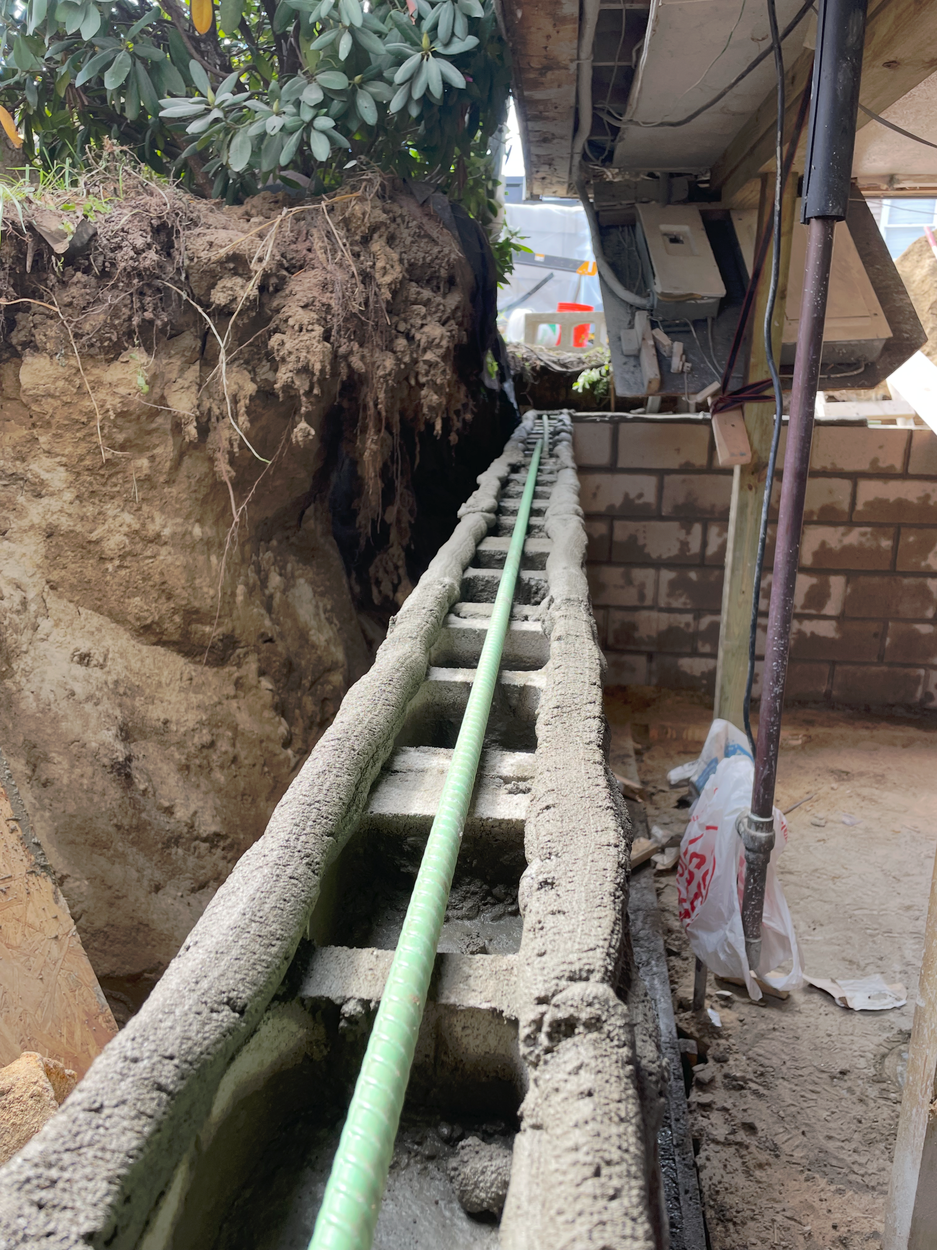 A concrete block wall under construction, featuring a green rebar line running along the center top.