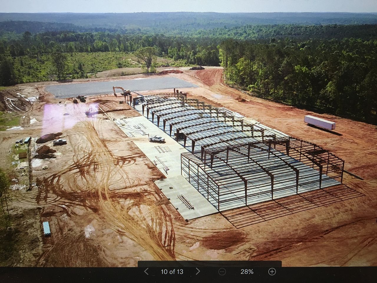 An aerial view of a building under construction in the middle of a forest.